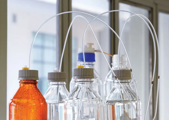 Laboratory reagents in bottles connected via tubes for lcms sarms testing.