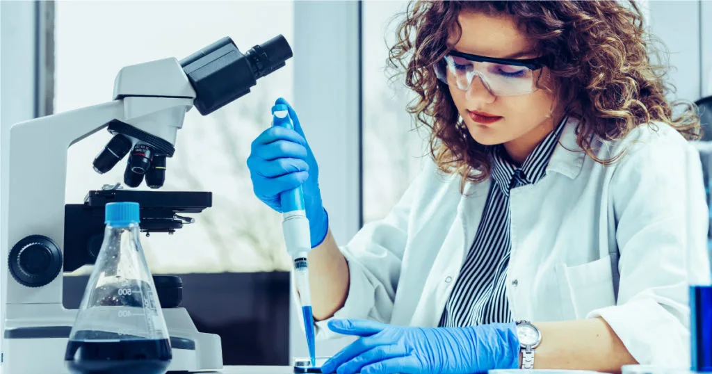 Laboratory researcher using pipette, microscope, and flask; focus on mk677 research experimentation and analysis.