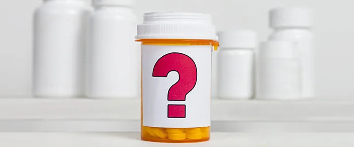 Prescription bottle with a question mark symbolizing uncertainty in medication contents against a blurred background.
