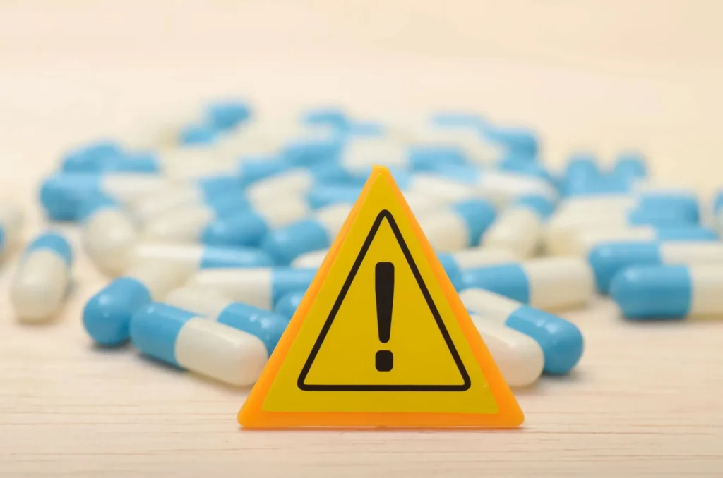 Warning sign with blue and white capsules, highlighting drug safety concerns.
